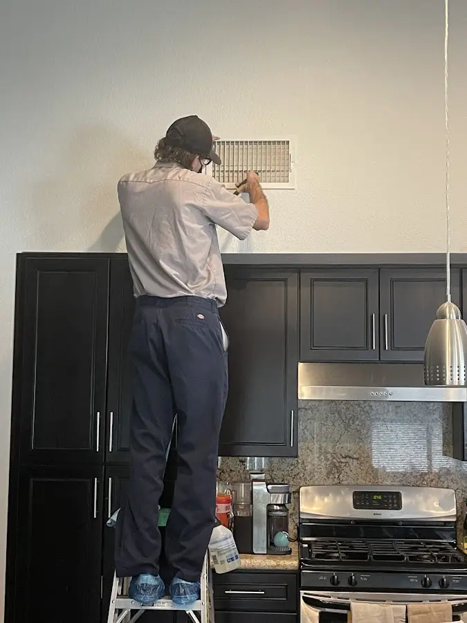 Technician inspecting an air vent during HVAC service in Las Vegas